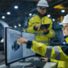 Image of Two People in Safety Vests and Hard Hats looking at a computer