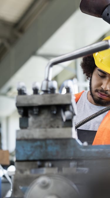 Young manual worker working on machinery
