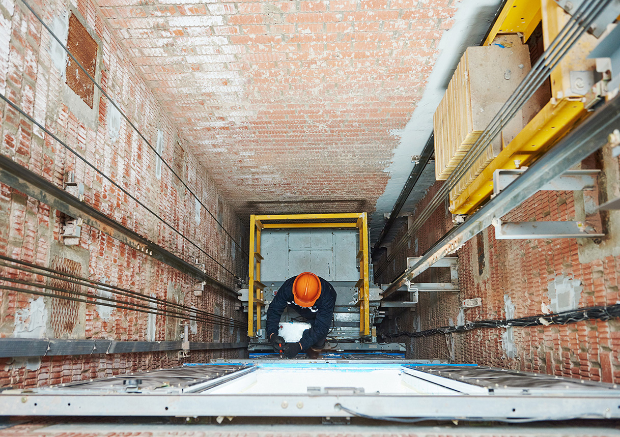 An elevator technician working inside a high-rise elevator hoistway