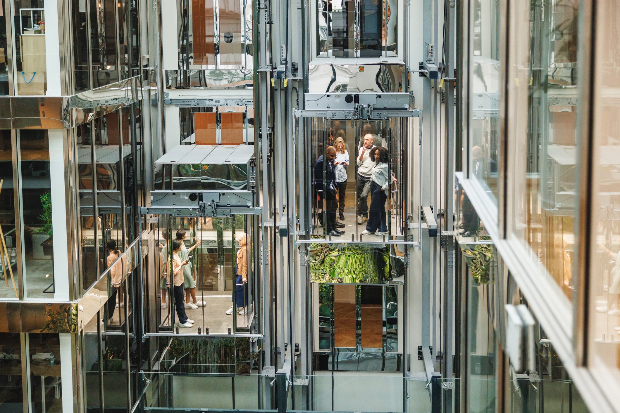 A group of business professionals riding transparent glass elevators inside a modern office building.